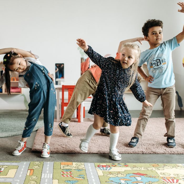 A group of young children in a classroom environment joyfully stretching, symbolizing the holistic approach to pediatric mobility and function taught in the Progressive GaitWays' hybrid learning model.