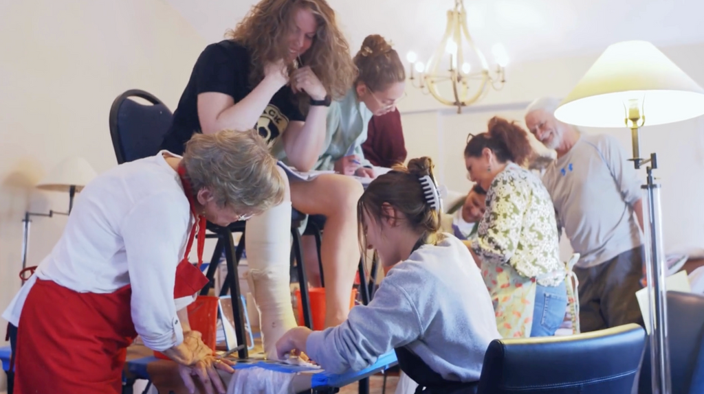 A group of clinicians participates in a hands-on workshop focused on lower leg casting. Two instructors guide the process while one participant’s leg is being wrapped for practice. This image represents Progressive GaitWays’ Conservative Management of Pediatric Equinus Deformity—Part 2: Labs with Serial Casting, where clinicians learn effective strategies for managing equinus deformity using serial casting.